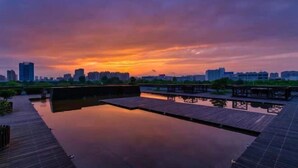 A serene waterfront area with wooden walkways and a calm water body reflecting the sunset. - Metropark Hotel Yancheng (Yancheng)