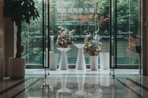 A reception area with a glass wall, potted plants, and floral arrangements. - Metropark Hotel Yancheng (Yancheng)