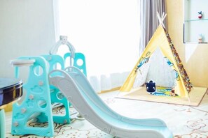 A children's play area with a slide, a play tent, and a small table with toys. - Metropark Hotel Yancheng (Yancheng)