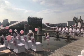 A rooftop venue with white chairs and pink balloons, overlooking a cityscape. - Metropark Hotel Yancheng (Yancheng)