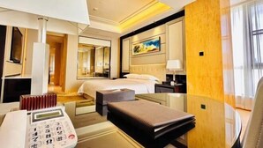 A hotel room with a bed, bedside table, lamp, and a painting on the wall. - Metropark Hotel Yancheng (Yancheng)