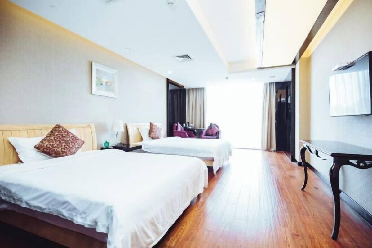 A hotel room with two beds, a desk, and a TV.