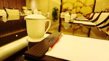 Una taza sobre un posavasos, un bloc de notas y un bolígrafo sobre una mesa.