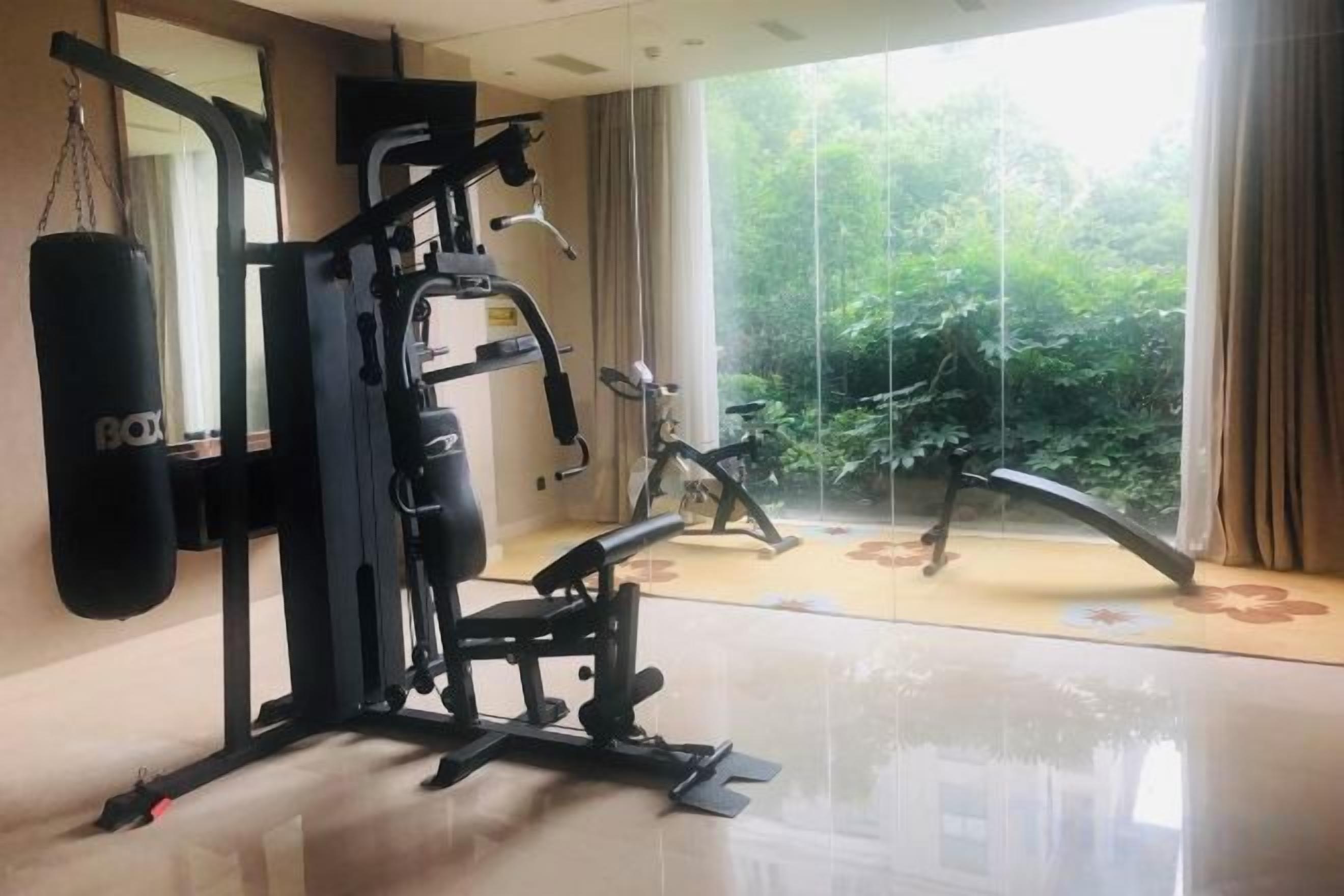 A home gym with a stationary bike, a punching bag, and weightlifting equipment.