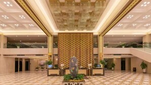 A spacious lobby with a central decorative sculpture, a patterned wall, and a tiled floor. - Metropark Hotel Yancheng (Yancheng)