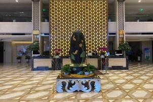 Un vestíbulo con mostrador de recepción, una planta ornamental y un diseño de pared con motivos.