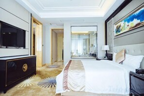 Habitación de hotel con una cama grande, televisión, cómoda y un cuadro en la pared.