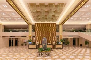 A spacious lobby with a patterned floor, a central decorative wall, and a reception desk. - Metropark Hotel Yancheng (Yancheng)