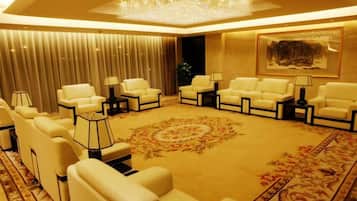 Um lounge de hotel com diversas áreas de estar, um candelabro e um tapete grande.
