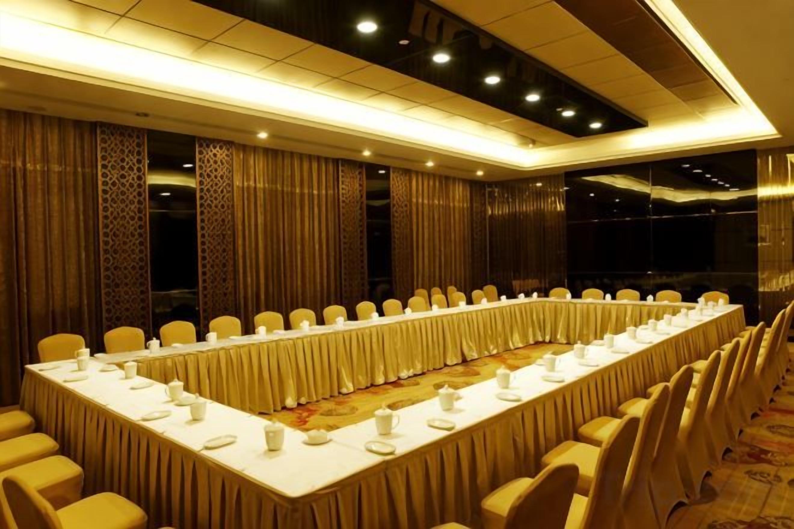 Una sala de conferencias con una larga mesa, sillas y piso alfombrado.