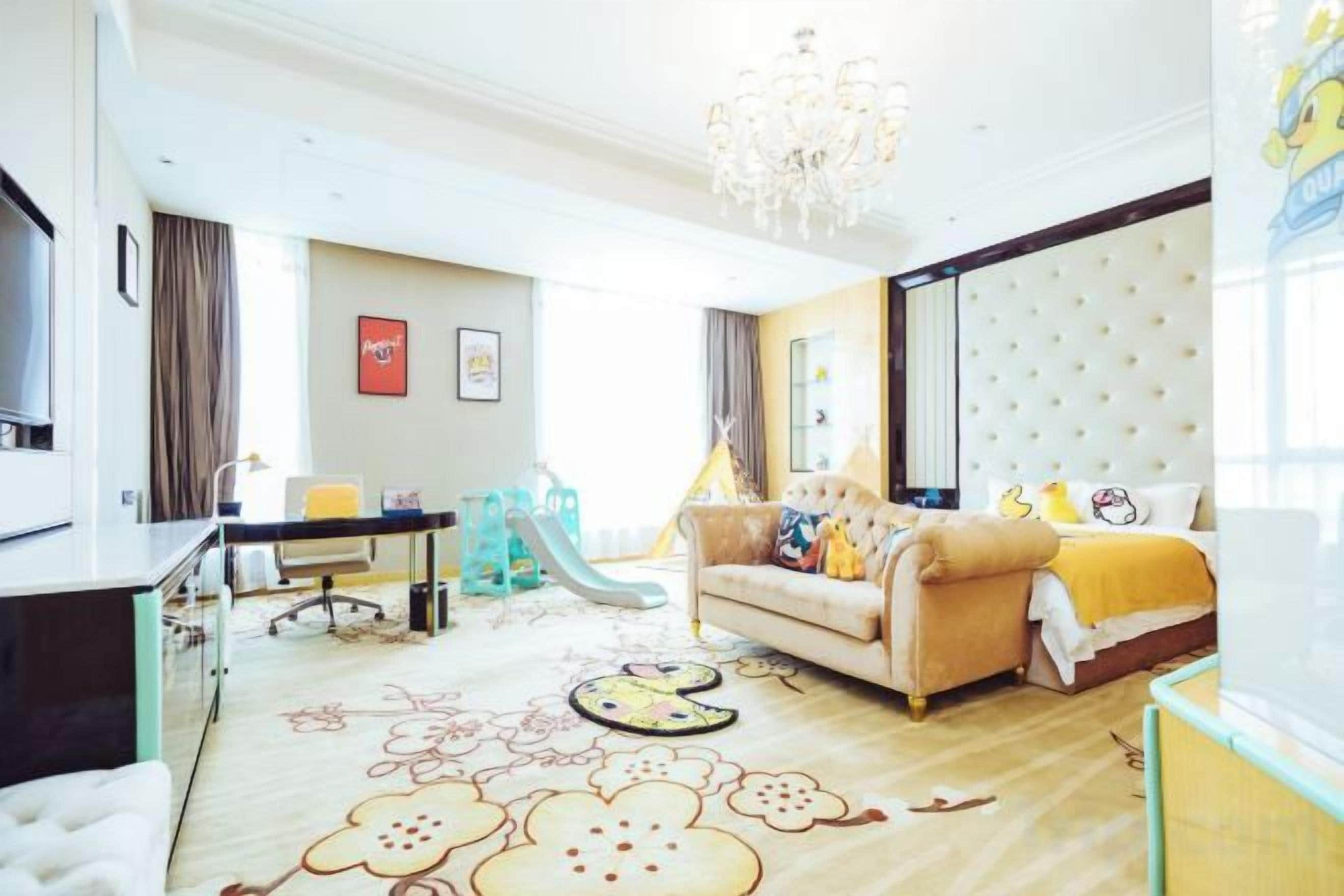 A modern living room with a sofa, a dining table, and a chandelier.