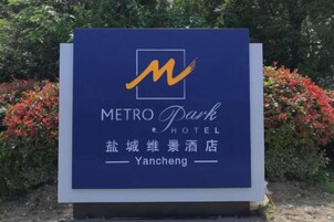 Un letrero para el Metro Park Hotel con un logotipo estilizado 'M', nombre en inglés y chino, y un nombre de ubicación.