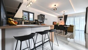 Een moderne keuken met een centraal eiland, barkrukken en een zithoek met een bank en tafel.