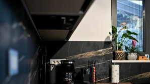 Een moderne keuken met een zwart aanrecht, een koffiezetapparaat en een schaal met fruit.