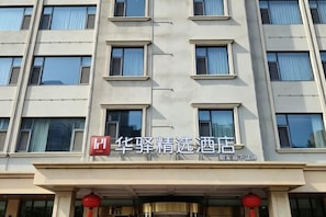 A hotel facade with multiple windows, a prominent red sign, and traditional red lanterns. - Home Inn Plus (Rizhao Shandong Road Shiwutian Branch) (Rizhao)