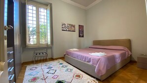 A bedroom with a bed, a window, a radiator, and a wall with artwork. - Miriam's little house in Piazza di Spagna, an oasis of elegance in the heart of Rome (Roma)