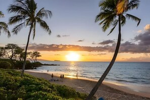 A beach with palm trees, a sunset, and a calm sea. - Walk to Beach! Pool, Hot Tub + AC Studio (Kihei)