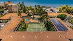 A residential area with a tennis court, solar panels, and a pool. - Walk to Beach! Pool, Hot Tub + AC Studio (Kihei)