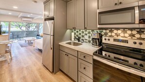 A modern kitchen with grey cabinets, a stainless steel microwave, and a built-in oven. - Walk to Beach! Pool, Hot Tub + AC Studio (Kihei)