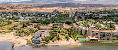 An aerial view of a coastal resort with a large hotel, beach, and surrounding residential area.