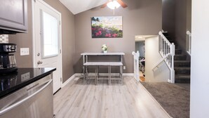 A kitchen with a built-in dishwasher, a dining area with a table and chairs, a ceiling fan, and a staircase leading to another level. - Spacious 4 bedroom house with AC, WiFi in, 2 living rooms, fenced, 2 car garage. (Omaha)