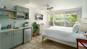 Une chambre moderne avec un lit, un bureau et une vue sur la verdure grâce à de grandes fenêtres.