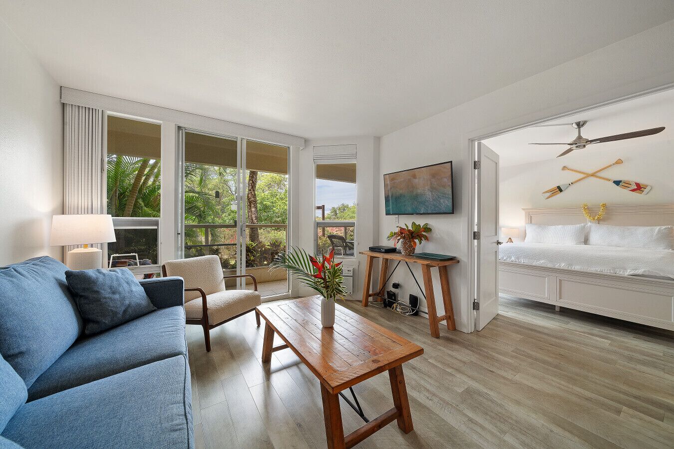 A modern living room with a blue sofa, a wooden coffee table, and a TV on a stand.