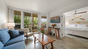 Una sala de estar moderna con un sofá azul, una mesa de centro de madera y un televisor sobre un mueble bajo.