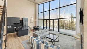 A modern interior with a kitchen, dining area, and living room with large windows.