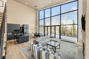 A modern interior with a kitchen, dining area, and living room with large windows.