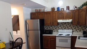 A kitchen with wooden cabinets, a stainless steel refrigerator, a microwave, and a stove. - Percy Quinn Vacation Rental A (McComb)