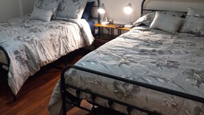 A bedroom with two single beds, each with a floral-patterned duvet, a bedside table with a lamp, and a small nightstand. - Percy Quinn Vacation Rental A (McComb)