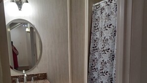 A compact bathroom with a toilet, sink, and shower curtain. - Percy Quinn Vacation Rental A (McComb)