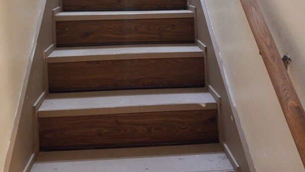 A wooden staircase with white walls and a wooden handrail. - Percy Quinn Vacation Rental A (McComb)