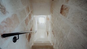 A narrow stairway with stone walls and a metal handrail, leading to a bright room at the top. - Fari by Monholiday - One Bedroom Apartment, Sleeps 4 (Monopoli)