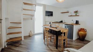 A kitchen with a dining table, chairs, a TV, and a small refrigerator. - Fari by Monholiday - One Bedroom Apartment, Sleeps 4 (Monopoli)