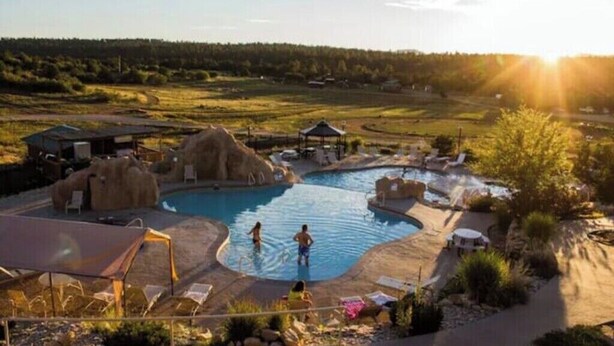 Un espace piscine comprenant plusieurs bassins, des chaises longues et un kiosque.