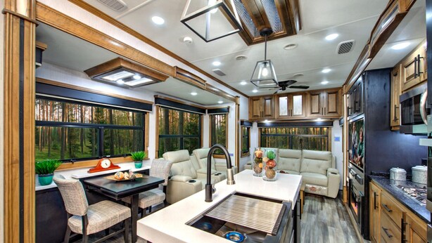 A modern RV interior with a kitchen, dining area, and seating space.
