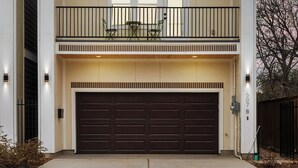 Une maison à deux étages avec un balcon, un garage et une allée.