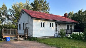 A single-story house with a red roof, a wooden deck, and a brick driveway. - South End Bungalow - 5 full bedrooms (Greater Sudbury)