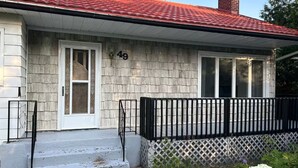 A single-story house with a red-tiled roof, a white door, and a black fence. - South End Bungalow - 5 full bedrooms (Greater Sudbury)