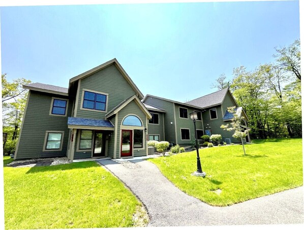 A two-story house with a front entrance, a driveway, and a well-maintained lawn.