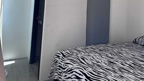 A modern bedroom with a zebra-patterned bedspread, recessed ceiling lights, and a dark accent wall.