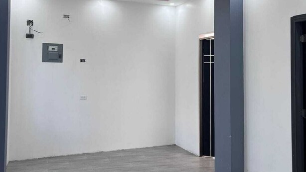 A spacious room with a wooden floor, white walls, and a ceiling with recessed lighting and a pink accent.