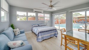 A bedroom with a bed, a blue sofa, a glass table, and a view of a swimming pool. - 5 Mi to Beaches: Melbourne Duplex w/ Heated Pool! (Melbourne)