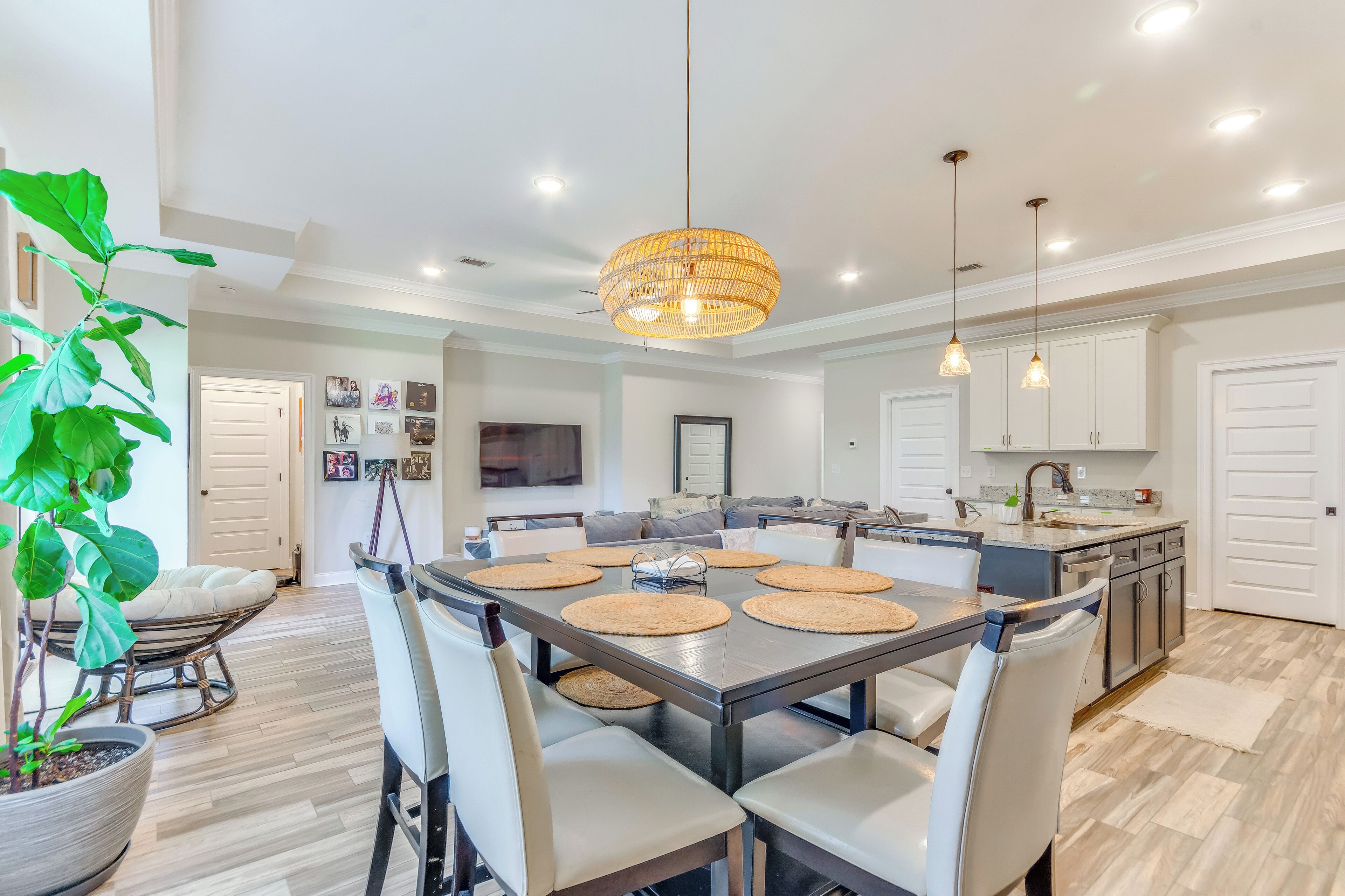 A modern kitchen with a dining area, featuring a large island, white cabinetry, and a hanging pendant light.