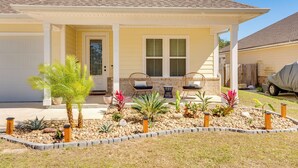 A single-story house with a covered porch, a garage, and a landscaped front yard with various plants and a small garden bed. - 2 Mi to Beach: Bright Navarre Home w/ Fire Pit! (Navarre)