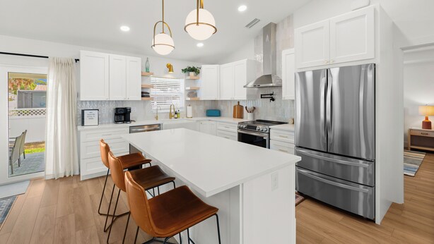 A modern kitchen with white cabinetry, stainless steel appliances, and pendant lighting.
