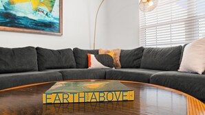 A modern living room with a sectional sofa, a coffee table with a book, a painting of a sailboat, and a floor lamp.