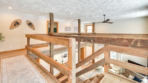 Amplia habitación con techo alto, vigas de madera y vista a otra estancia.